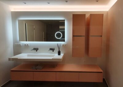 Moderne badkamer met spiegel met achtergrondverlichting en indirecte sfeerverlichting, geïnstalleerd door Elgeda